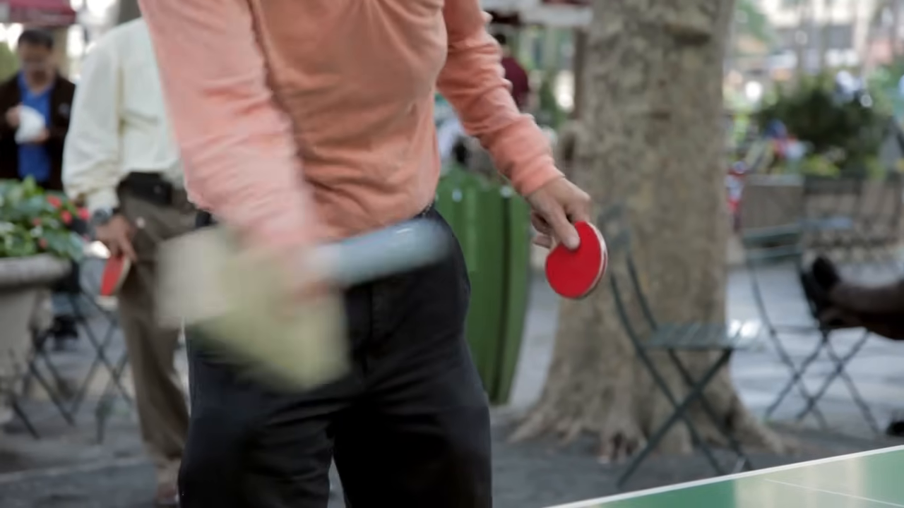 A player nicknamed "Crazy" demonstrates hitting the ping pong ball using a thick, rectangular block of wood instead of a standard paddle.
