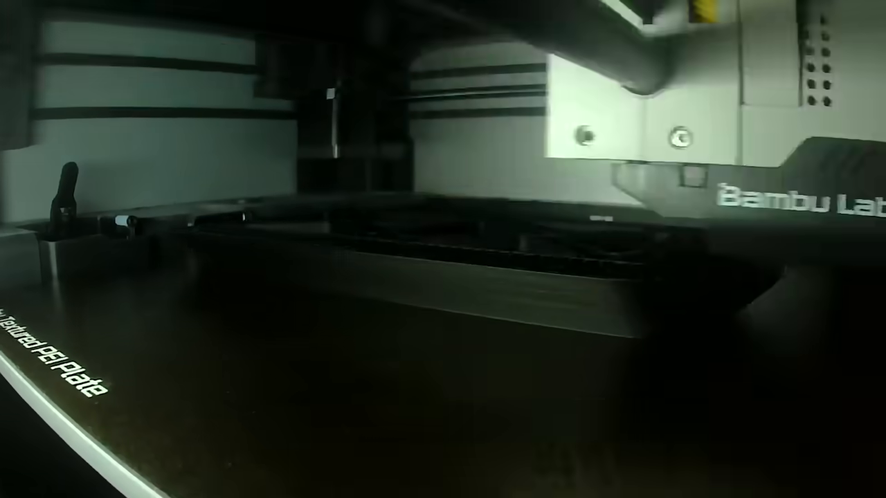 [01:12]  — A time-lapse view inside the printer chamber showing the black filament parts being printed.