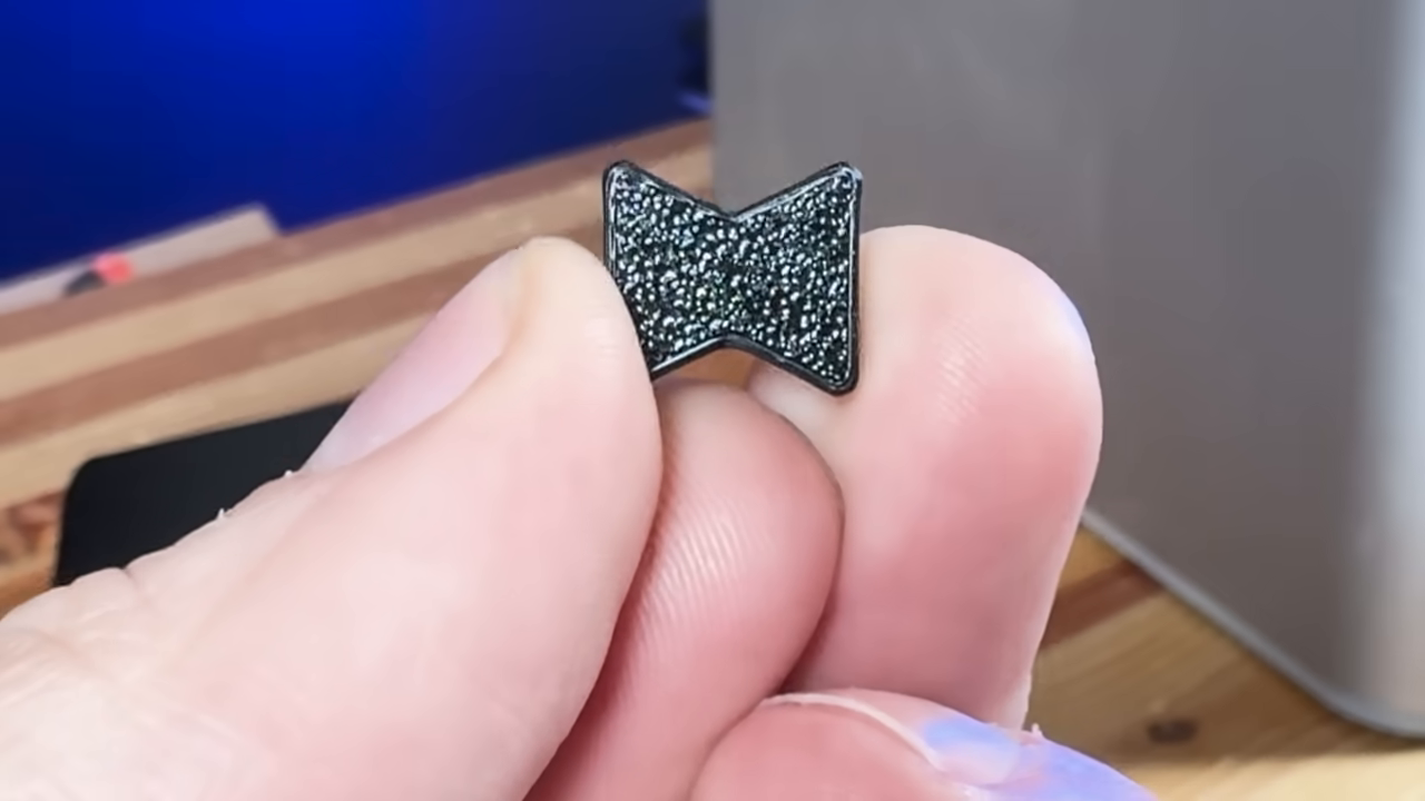 [02:04]  — A close-up showing a tiny, 3D-printed bowtie/butterfly connector held between two fingers.